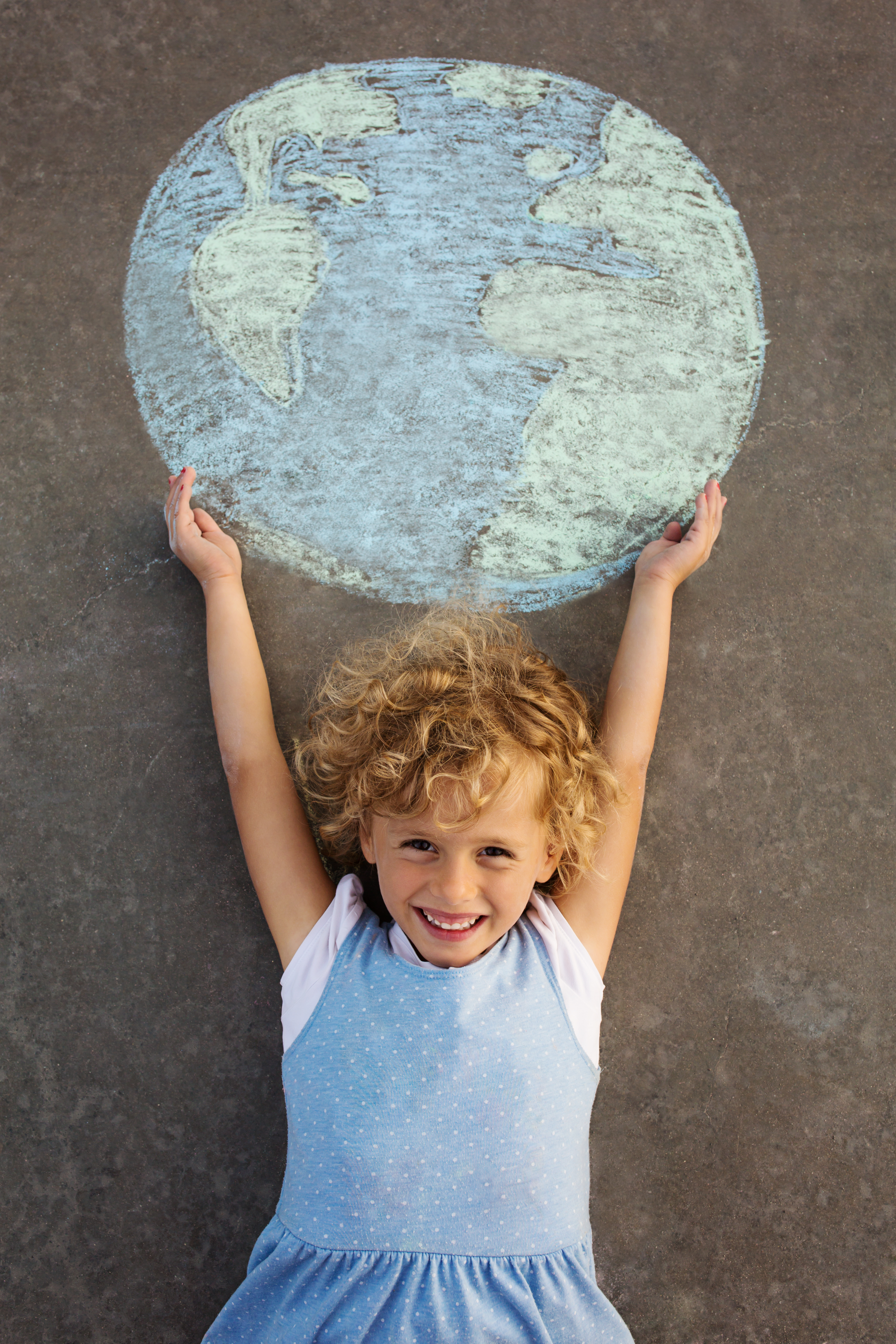 Child holding up a chalk drawing of earth