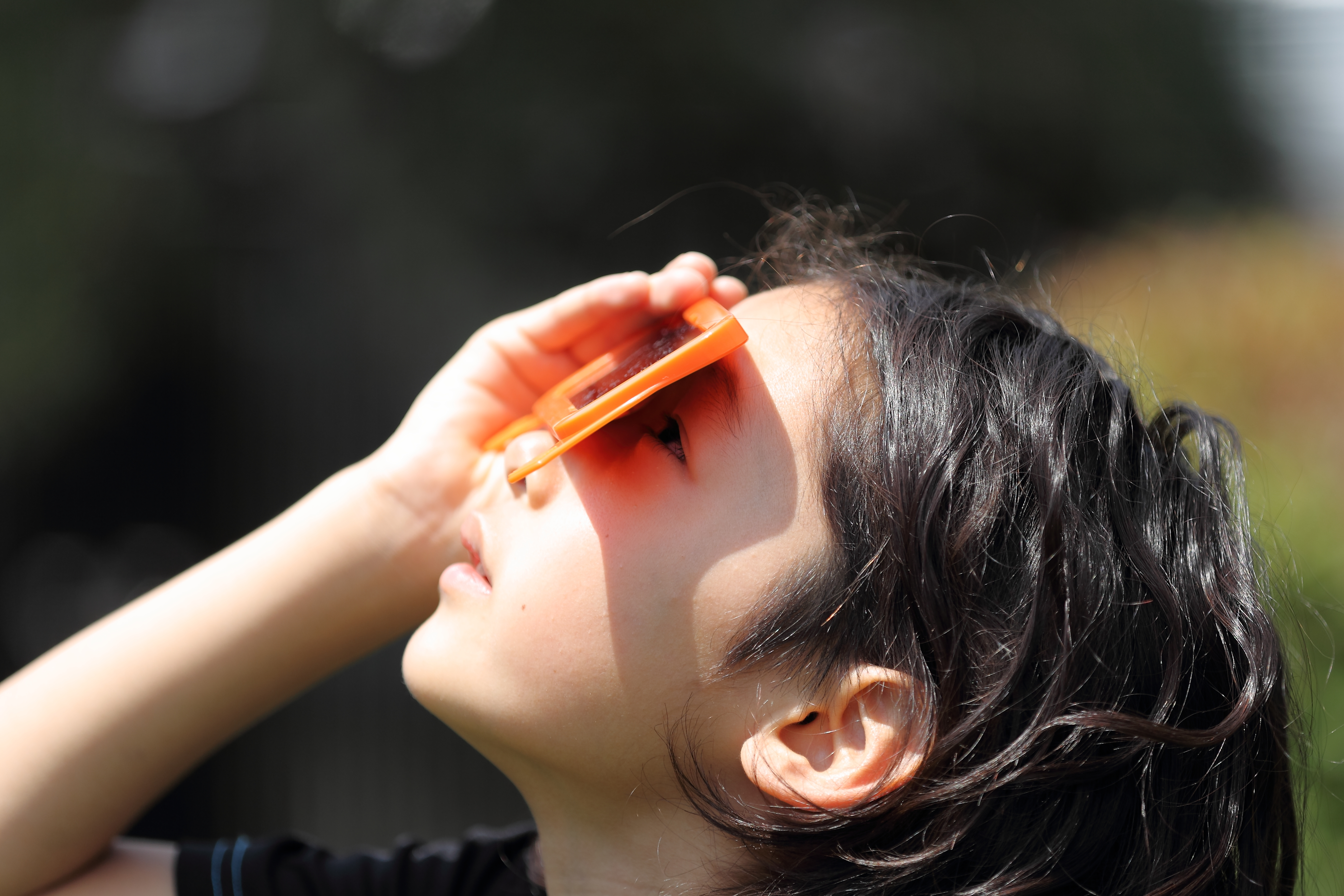 Child looking up at sky with solar viewing glasses