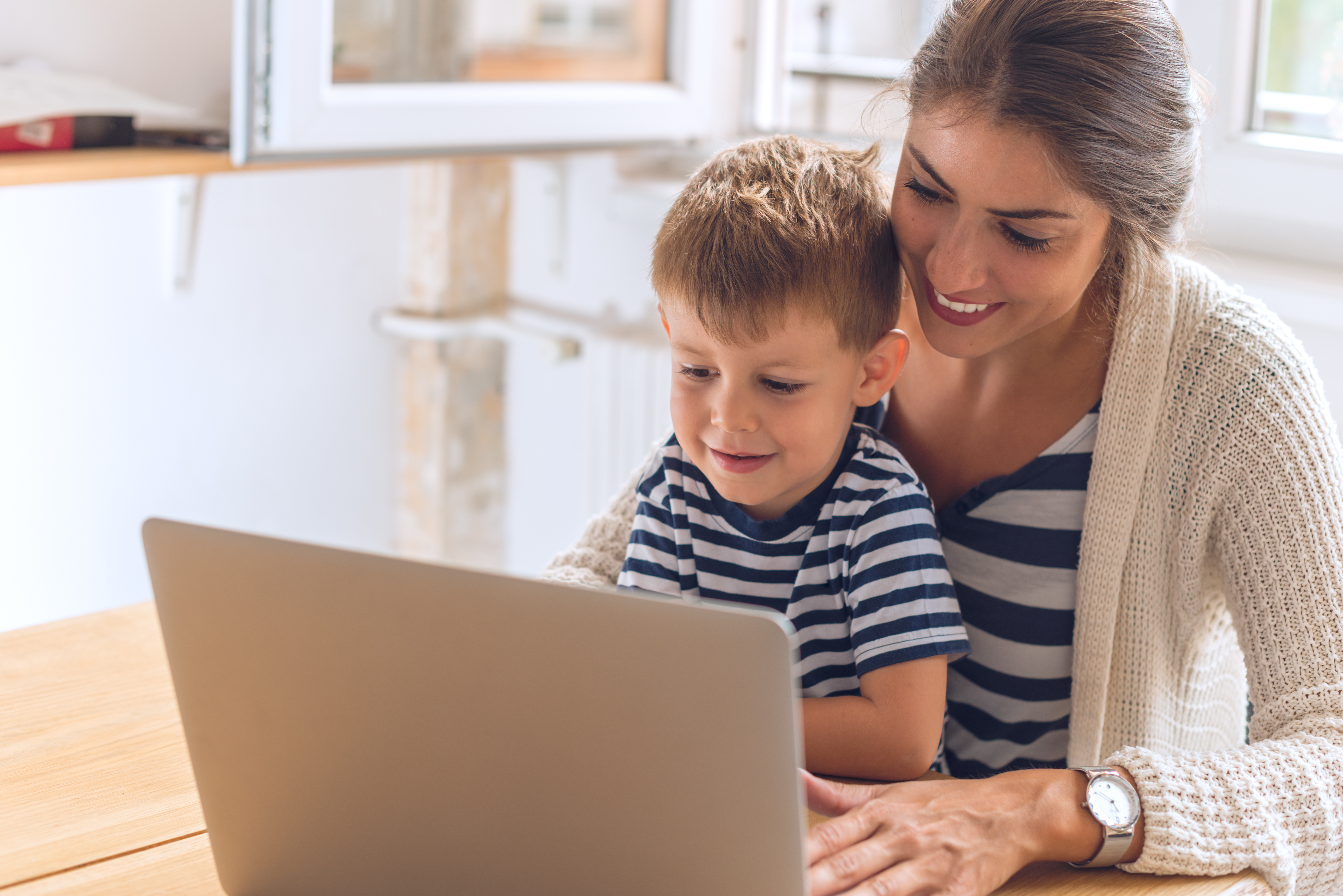 Woman and boy smiling while looking at a laptop