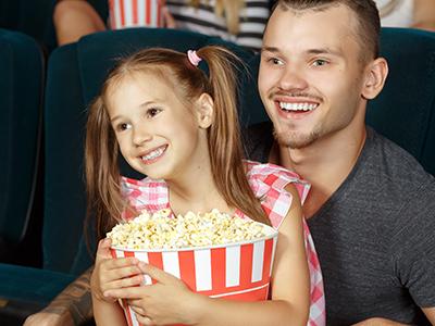 Girl and dad watching a movie with popcorn
