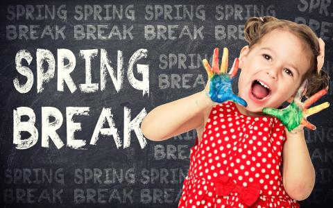 Girl with paint on her hands in front of chalkboard that says "Spring Break"