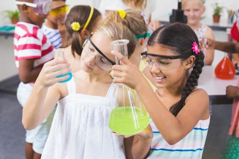 Two kids looking at beakers of liquids