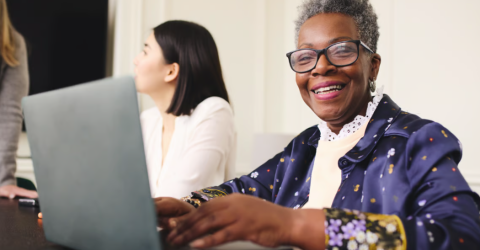 photo of older woman sitting with laptop smiling.
