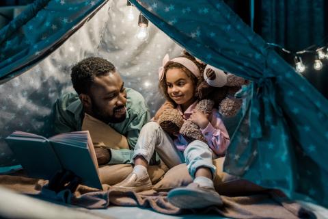 man and child inside tent reading