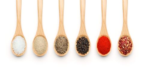 wooden spoons in a row with different colorful spices filling the spoons