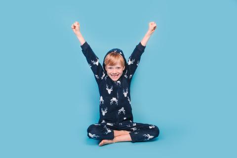 Happy girl in pajamas with her hands raised