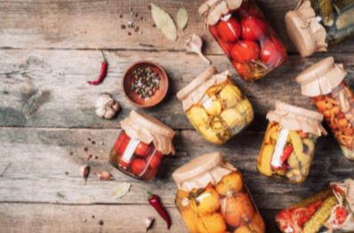 various canned garden produce laying out on a wood background.