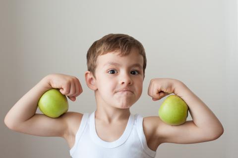 boy flexing his biceps with apples
