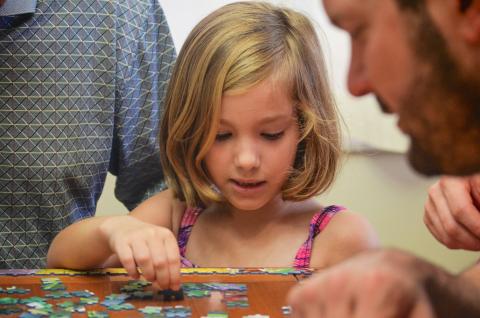 girl putting a puzzle together with help from man