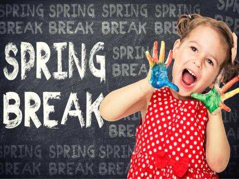 Girl with paint on her hands in front of chalkboard that says "Spring Break"