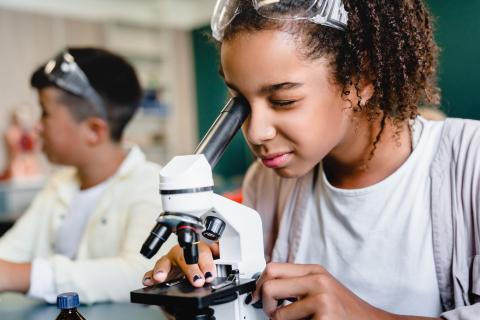 Girl looking through a microscope