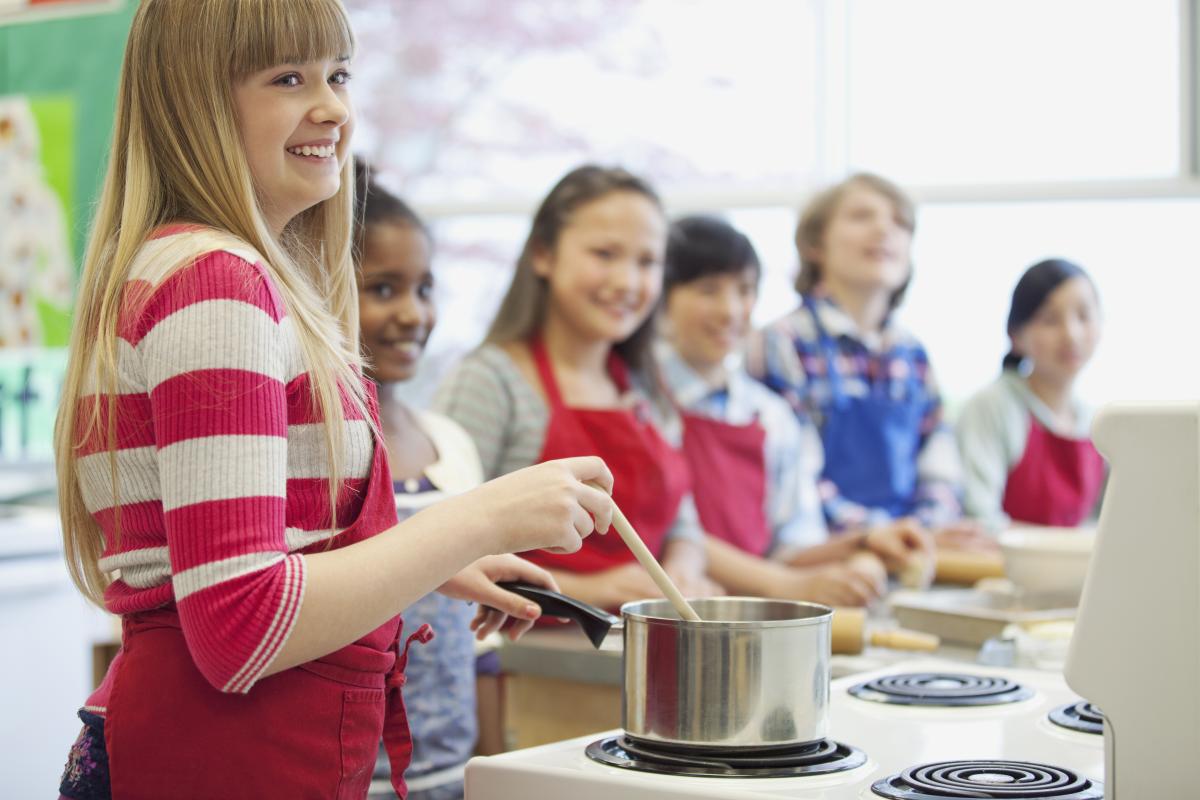 Group of kids wearing aprons and cooking