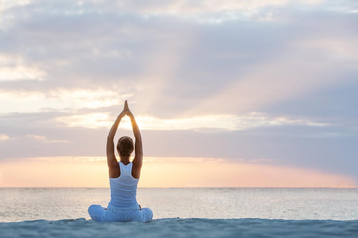 woman on beach doing yoga at sunrise