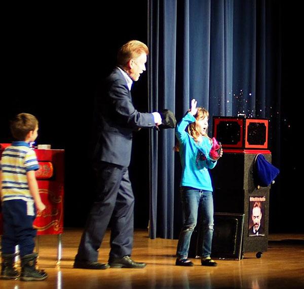 Magician helping two kids do magic tricks