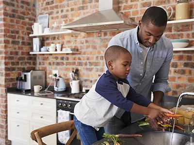 Young boy cooking in a kitchen with his father