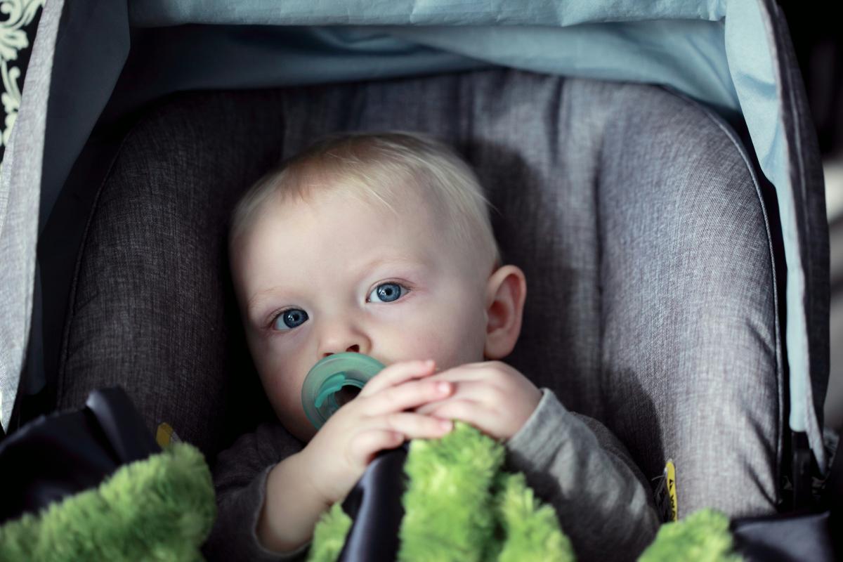 baby sitting in car seat with pacifier