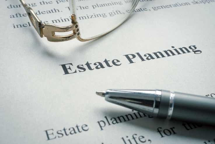 a close up on a paper that has the words estate planning on it and a pen and some glasses.